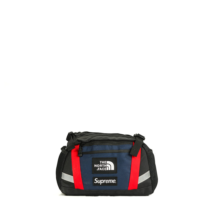 Black and blue duffel bag with red accents and Supreme and The North Face logos on a white background